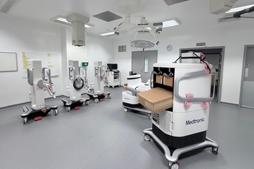 Robotic surgery system set up in a hospital theatre with multiple robotic arms and equipment